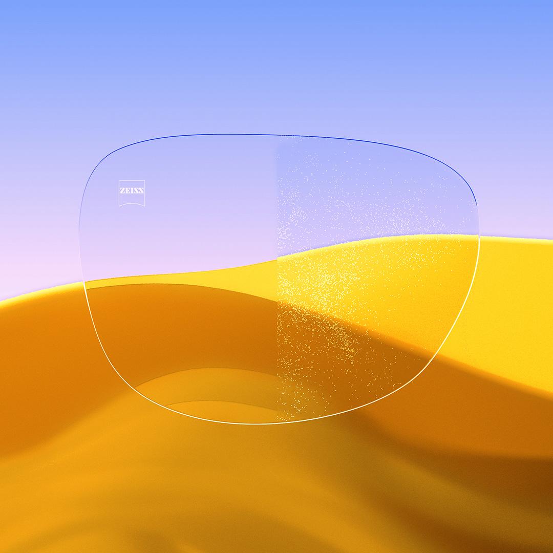 Uma lente dividida ao meio, com um lado nítido e limpo com ZEISS DuraVision Gold UV e um lado coberto de pó.