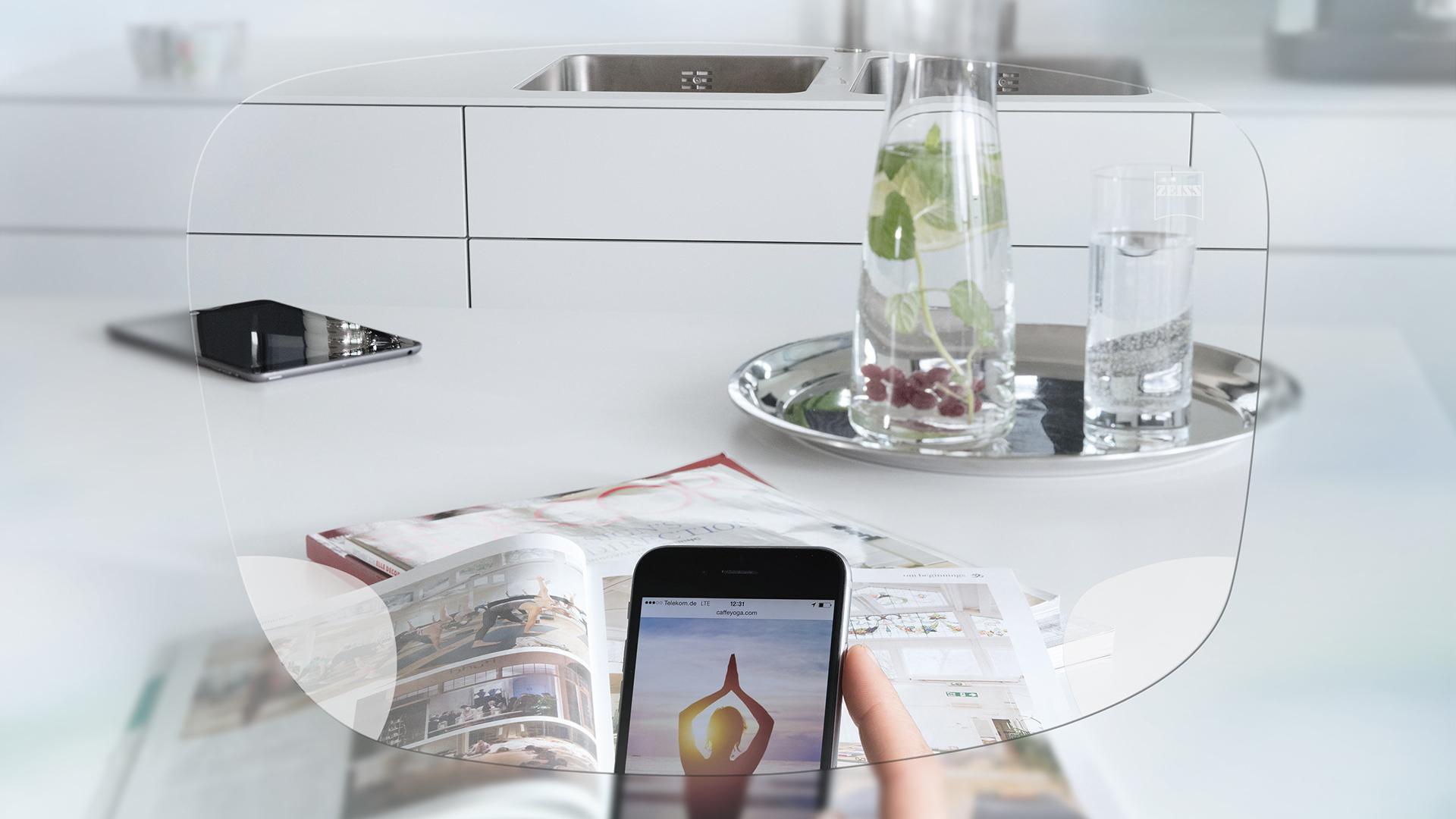 Visão através das lentes ZEISS EnergizeMe Monofocal de um ecrã do smartphone e de uma bancada de cozinha organizada. 