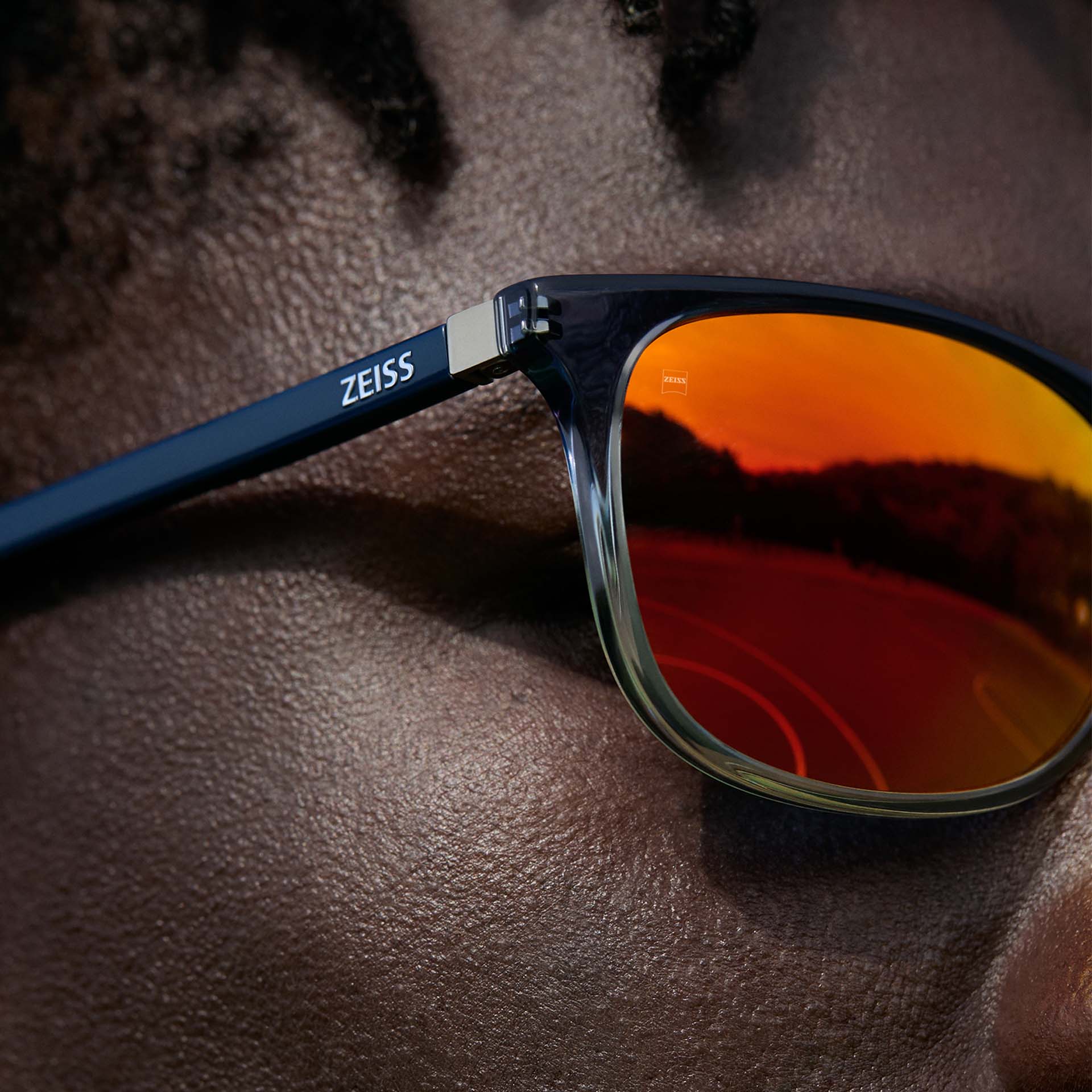 Grande plano de um homem com óculos da ZEISS com revestimento ZEISS DuraVision Mirror UV em laranja.