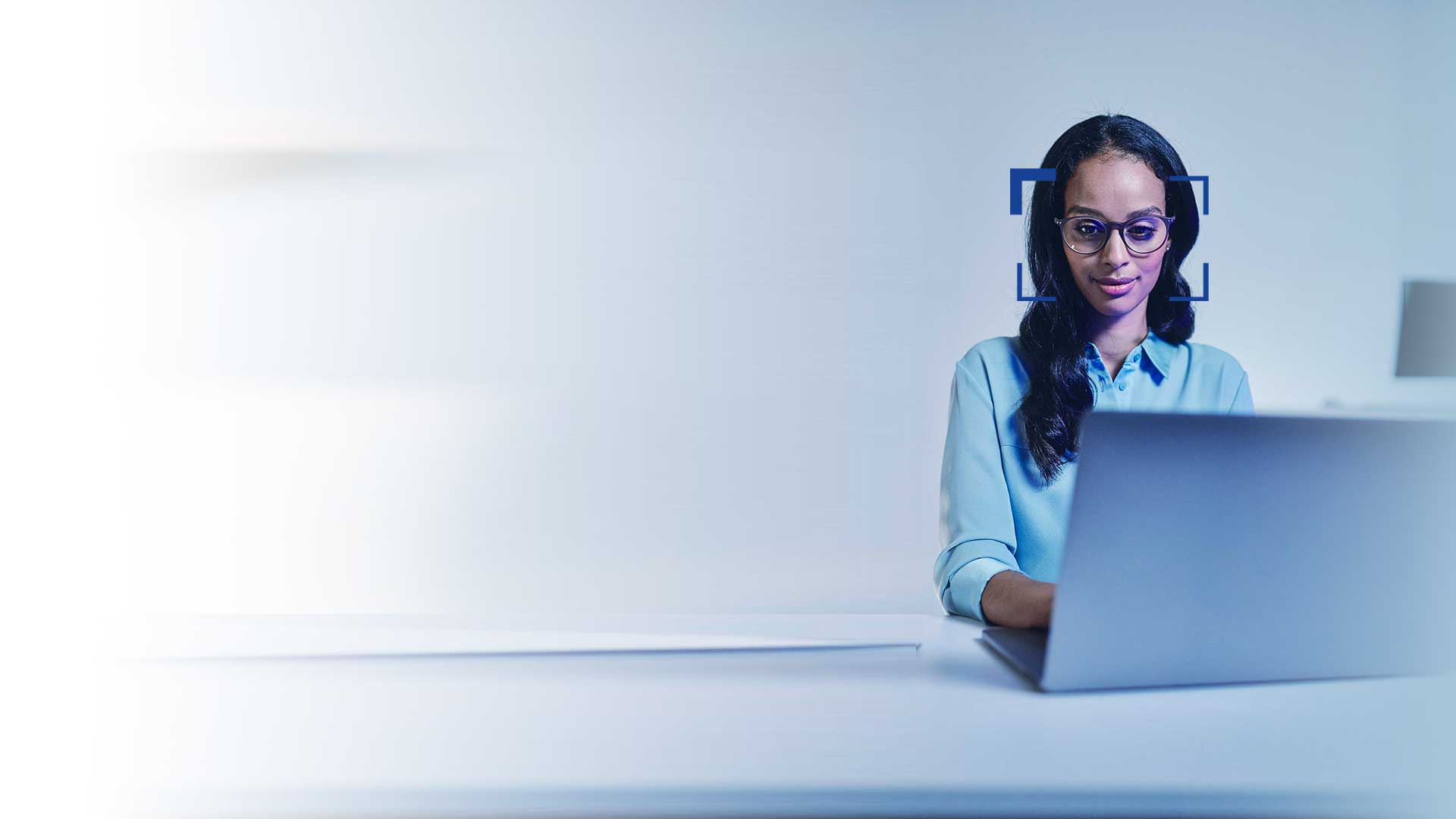 Mulher com cabelo preto e óculos a sorrir enquanto olha para um computador