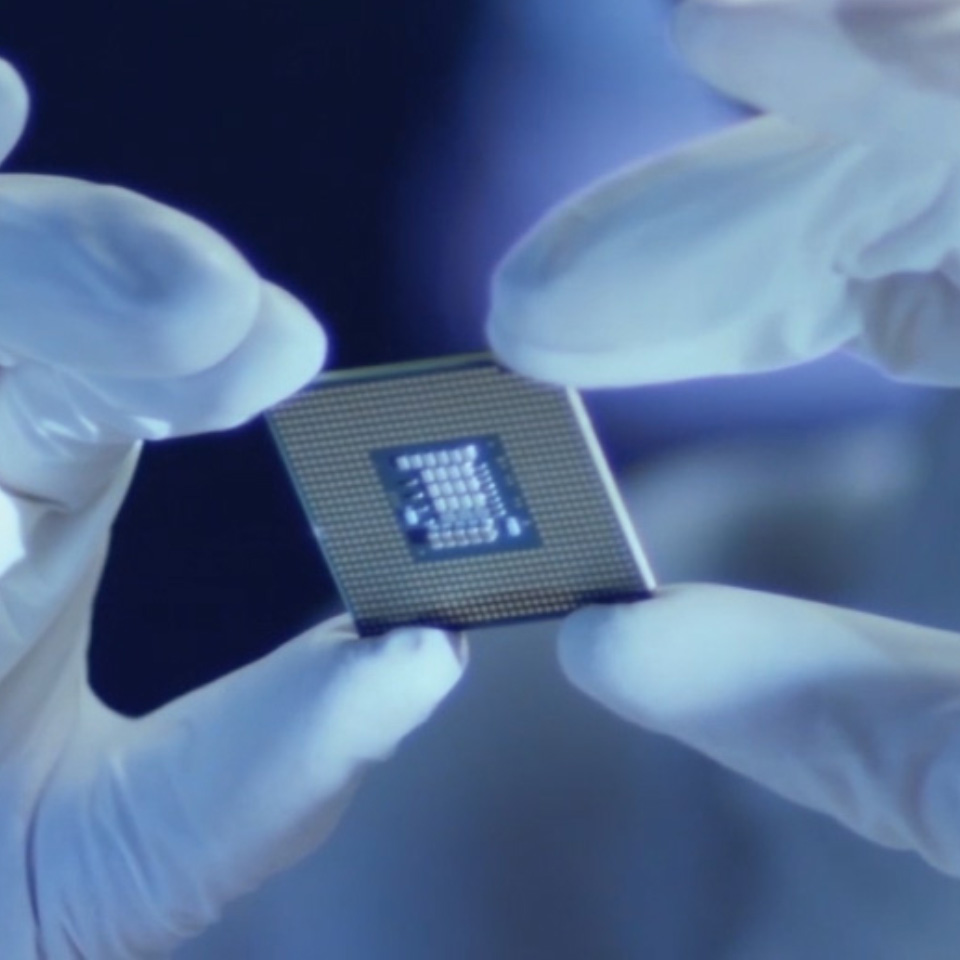 Imagem de um microchip na mão de uma pessoa com luvas de laboratório. 