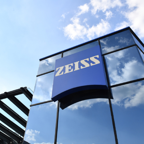 Imagem de um edifício de vidro moderno com um grande logótipo da ZEISS. 