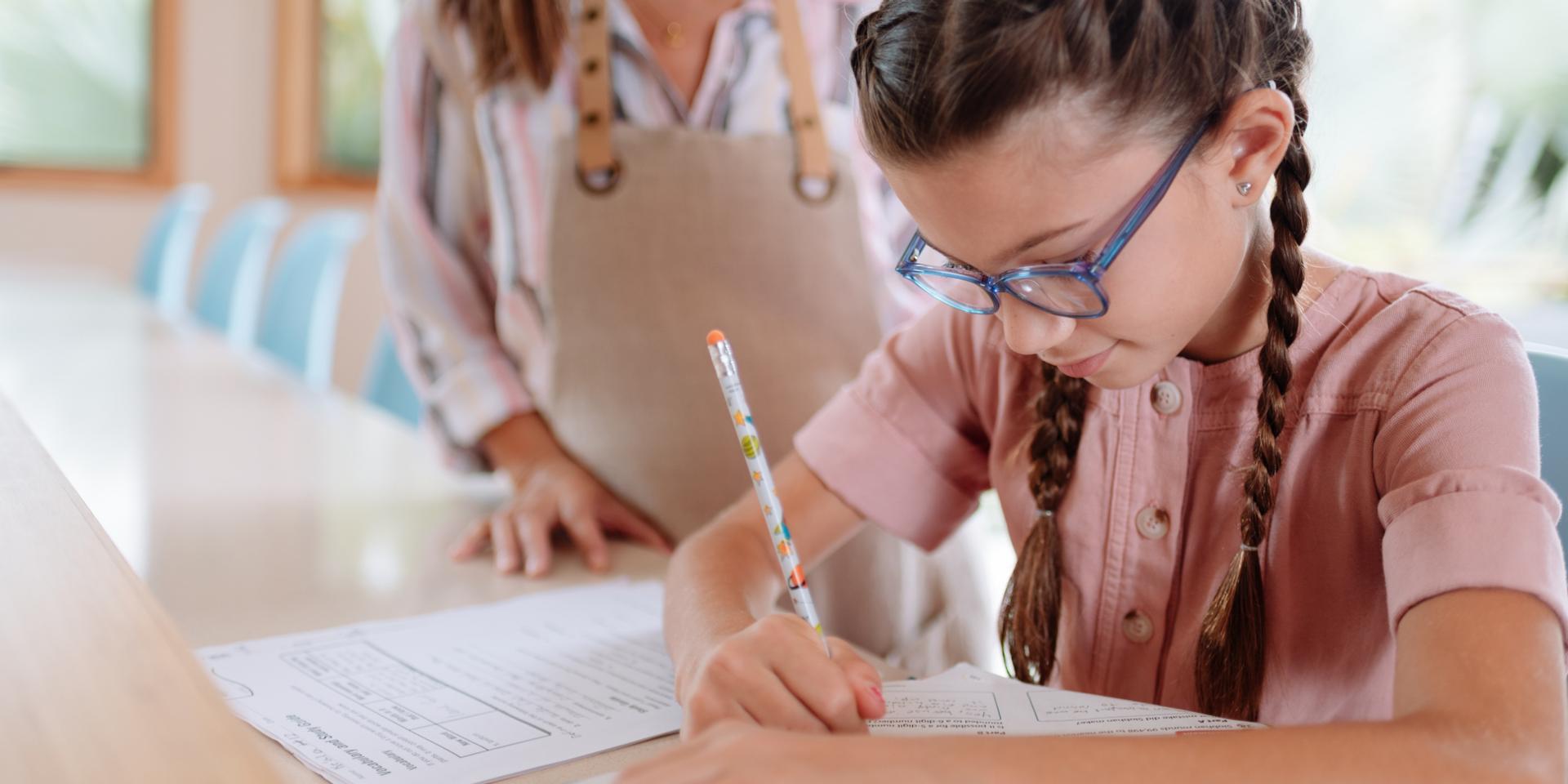 Menina de óculos a escrever com um lápis