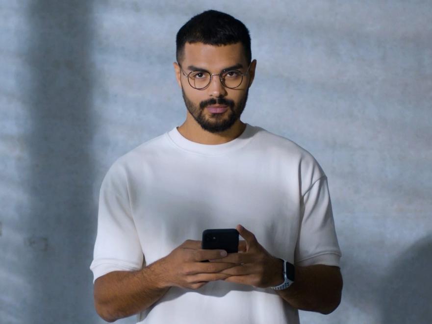 Um jovem com óculos BlueGuard a mexer no seu telemóvel.