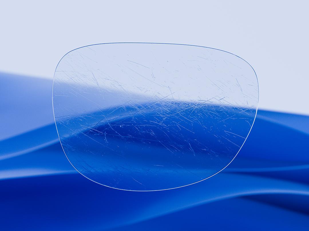 Imagem dividida que mostra, de um lado, uma lente ZEISS caracterizada pela sua nitidez e limpeza, e, do outro lado, uma lente convencional riscada, evidenciando o contraste na durabilidade. 
