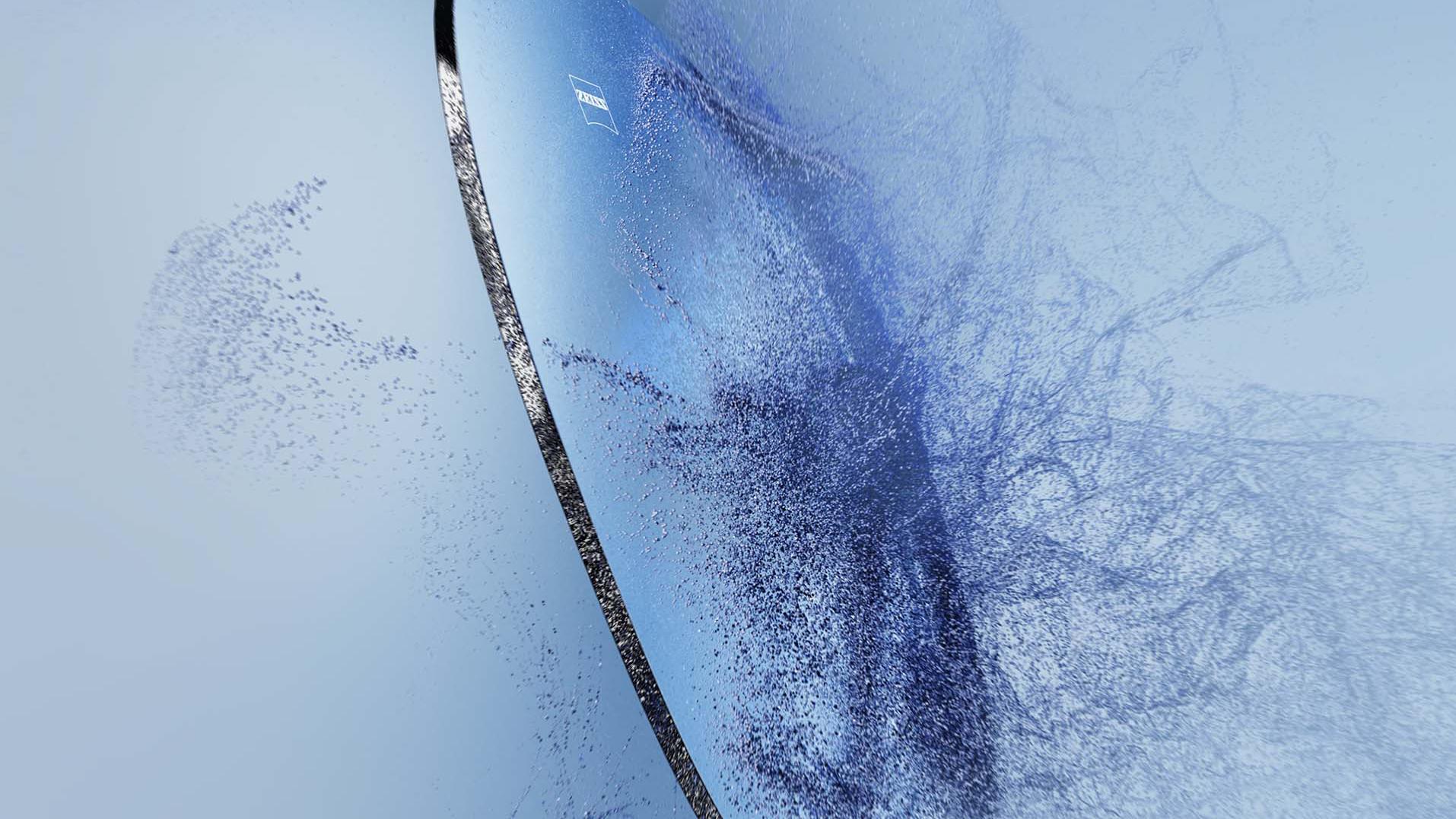 Areia a ser projetada contra uma lente de óculos com o logótipo da ZEISS
