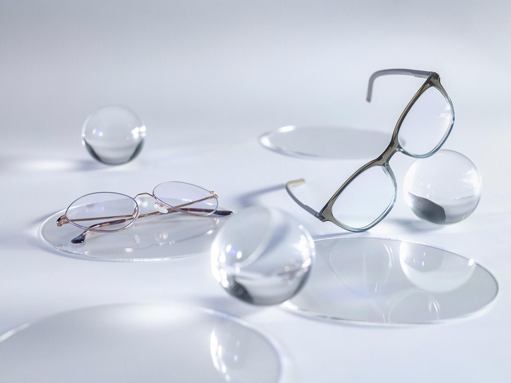 Óculos com lentes ZEISS com revestimento DuraVision® Silver que não apresentam reflexos, em comparação com as esferas de vidro circundantes.