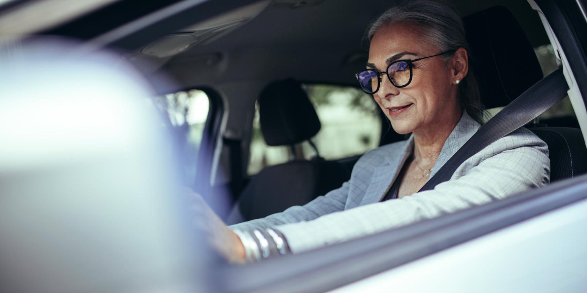 Mulher madura num automóvel a usar óculos com lentes ZEISS DriveSafe.