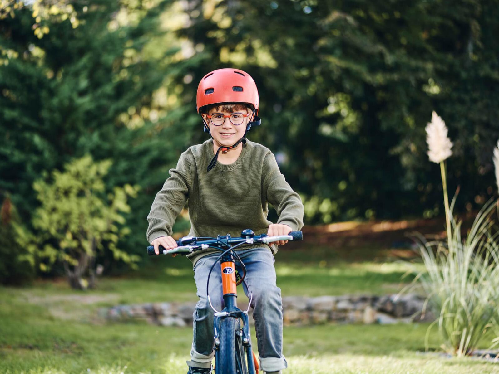 Menino com lentes ZEISS para a gestão da miopia a andar de bicicleta ao ar livre.