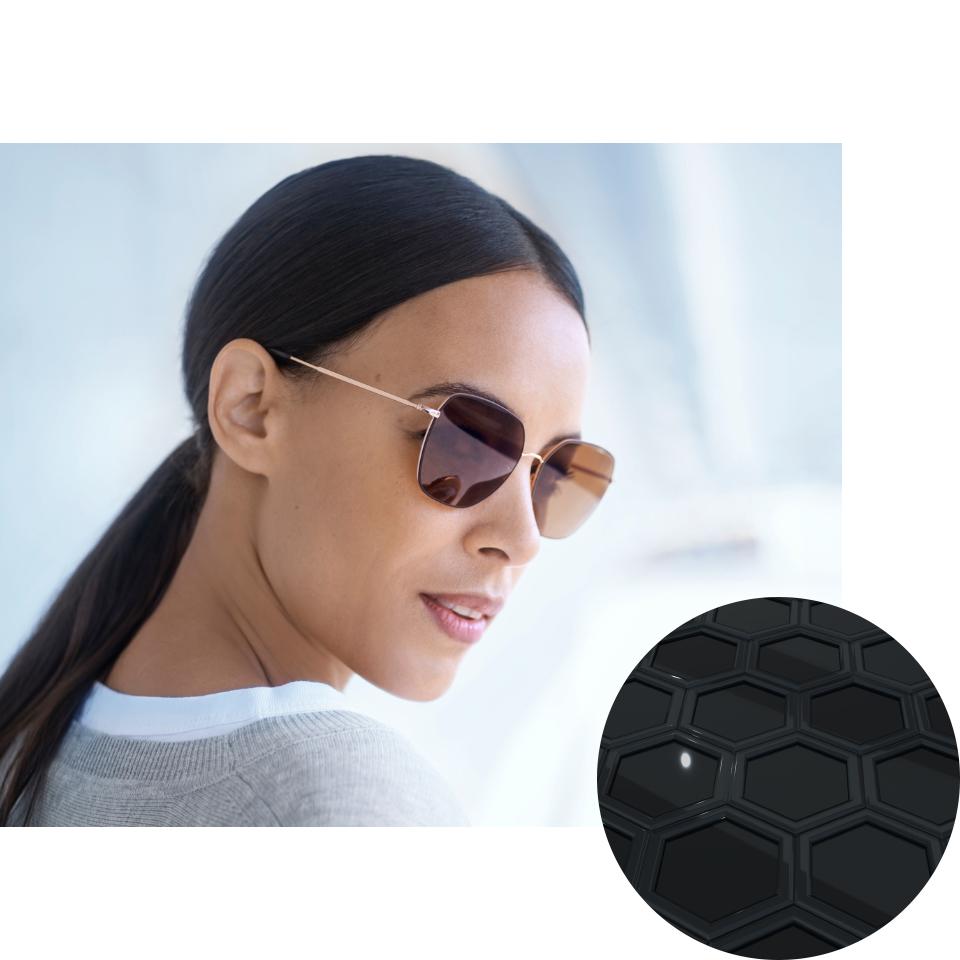 Mulher a usar óculos com ZEISS PhotoFusion X no modo escurecido, com uma imagem dos compostos de corantes desdobrados. 