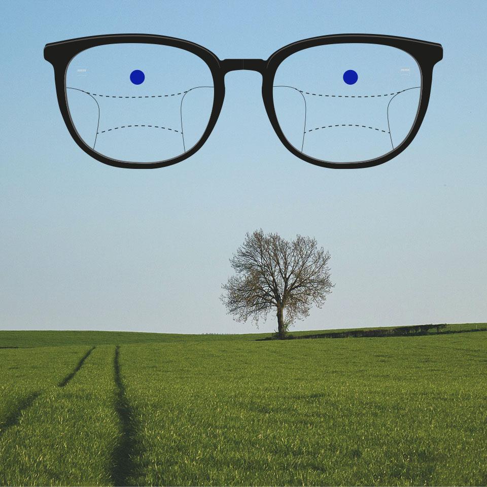 Uma armação com lentes progressivas e linhas esquemáticas que indicam as diferentes zonas de visão. As diferentes partes da lente estão assinaladas: visão ao longe - parte superior das lentes.