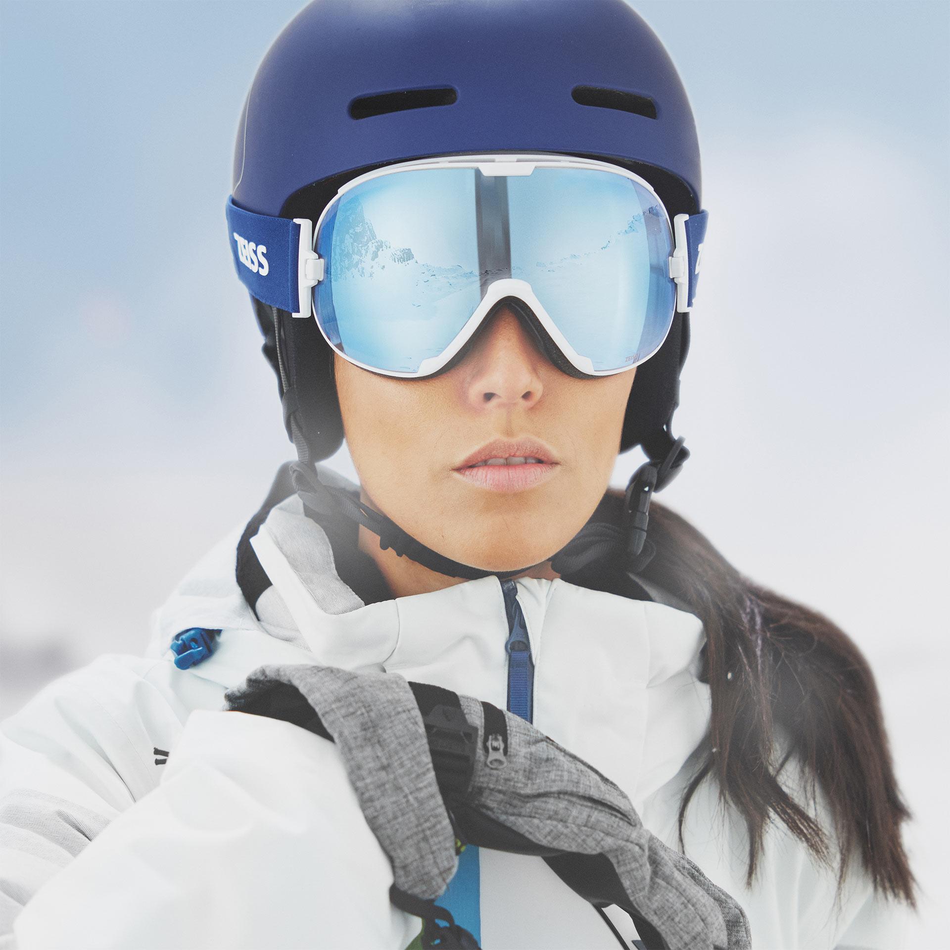 Mulher com capacete azul e máscara ZEISS para a neve com lente azul espelhada.