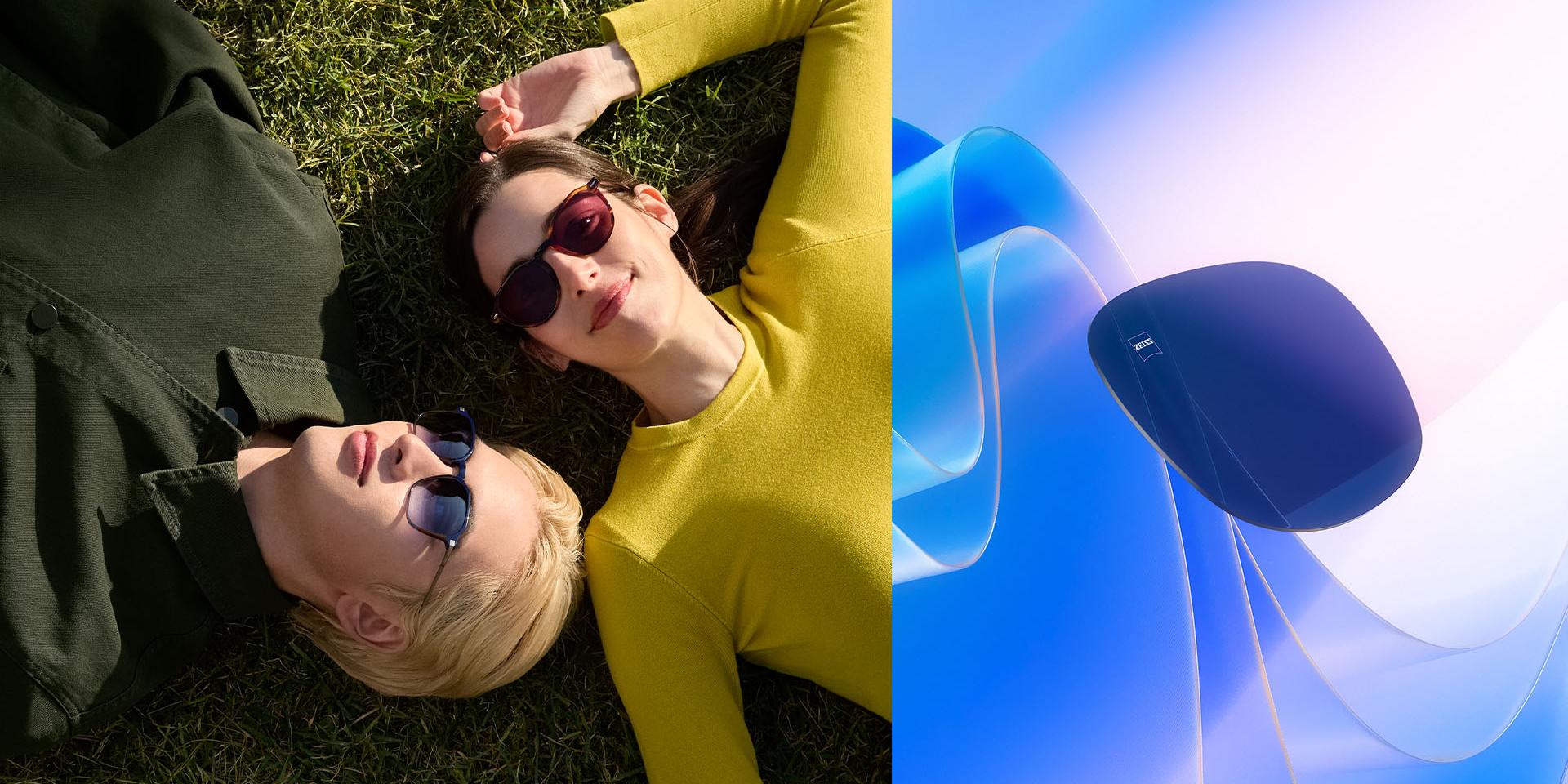 Homem e mulher a usar óculos de sol graduados da ZEISS, relaxando na relva a olhar para o céu. Representação gerada por computador de uma lente colorida a flutuar em direção à luz solar, ilustrando as suas capacidades de bloqueio dos raios UV.