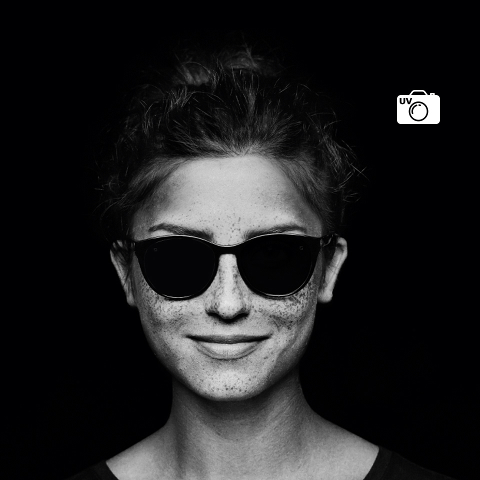 A mesma mulher com lentes incolores, vista através de uma câmara normal e de uma câmara UV. Com a câmara UV, a lente parece preta, o que indica que não deixa passar os raios UV.  