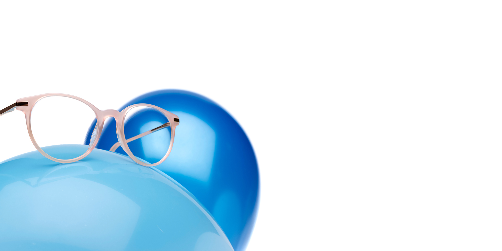 As lentes ZEISS MyoCare numa armação bege rosado são mostradas num balão azul claro. Em segundo plano está outro balão azul ligeiramente mais escuro.