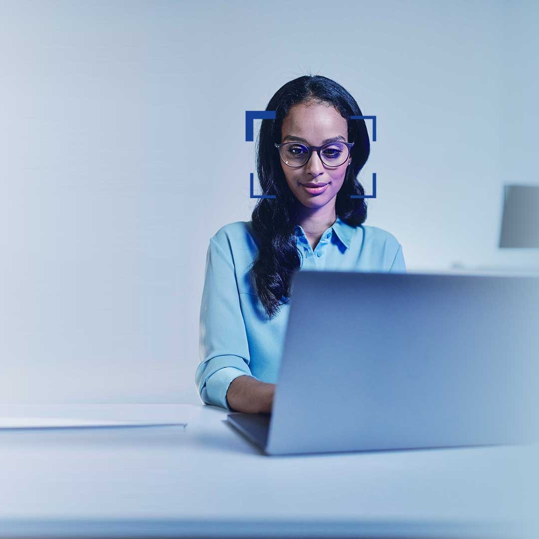 Mulher com cabelo preto e óculos a sorrir enquanto olha para um computador