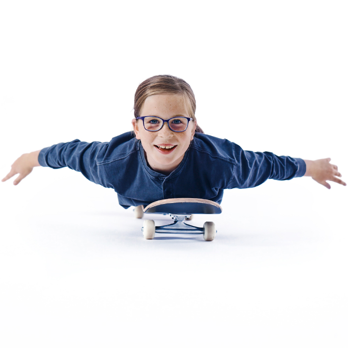 Menina de óculos deitada de bruços sobre um skate.